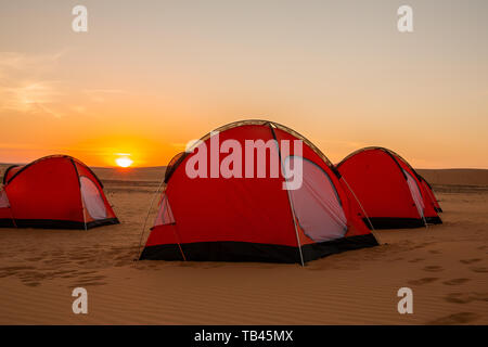 3 Orange 2 Mann Zelte in der westlichen Wüste des Sudan warf für die Nacht in den hellen gelben Sonnenuntergang mit der Sonne am Horizont Stockfoto