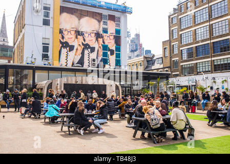 Pop Up Outdoor Essen mit Menschen essen outiside und Wandbild Street Art feiern Andy Warhol in der Alten Truman Brauerei, Ely's Yard, Shoreditch Stockfoto