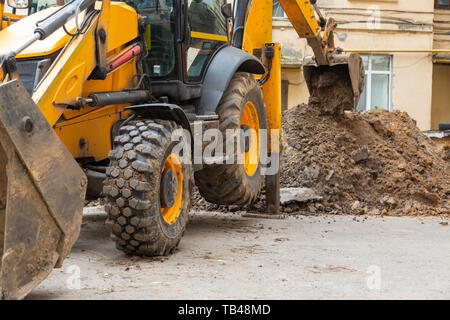 Bagger gräbt ein Graben. Reparaturarbeiten im Innenhof eines Wohnhauses. Stockfoto