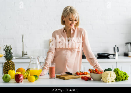 Blonde schwangere Frau auf Zutaten in der Küche auf der Suche Stockfoto