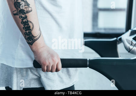 Anzeigen von Übergewicht tätowierten Mann laufen auf Laufband im Sportzentrum 7/8 Stockfoto