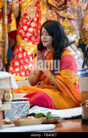 Eine schöne Hindu Priesterin betet und meditiert, während führende ein Gebet Service an einem Tempel in Jamaica, Queens, New York. Stockfoto