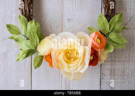 Hohen Winkel in der Nähe von einem kleinen Kranz mit hellem Gelb und rosa Papier Rosen, Dekoration Stockfoto