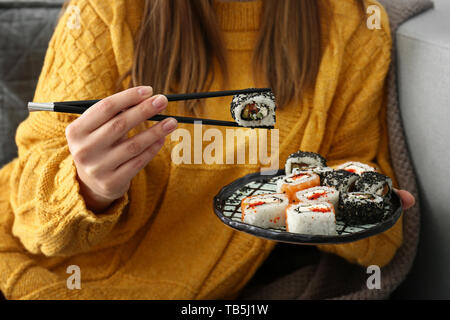 Frau essen lecker Sushi Rollen zu Hause. Stockfoto