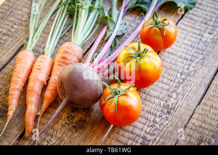 Karotten, rote Beete, Tomaten und nur im Garten auf Holzbrettern abgeholt. Frisches Gemüse. Ansicht von oben. Stockfoto