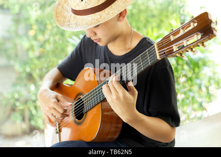 Asiatischer Mann spielen eine klassische Gitarre in der Natur Stockfoto