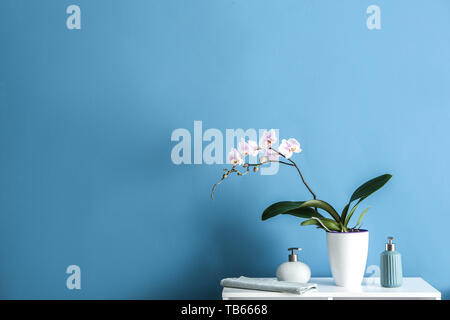 Schöne Orchidee und Flaschen Parfüm auf Tisch gegen Farbe Hintergrund Stockfoto