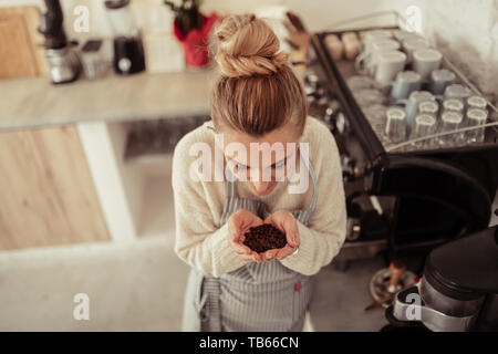 Kaffeebohnen. Schöne barista stehen in der Nähe der Kaffeemaschine mit einer handvoll frisch gerösteten Kaffeebohnen. Stockfoto