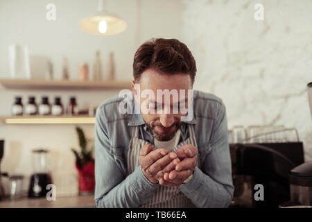 Lieben ihren Job. Lächelnd cafe Eigentümer riechen frisch gerösteten Kaffeebohnen in seinen Händen. Stockfoto