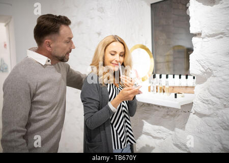 Attraktiven Duft. Wunderschöne lächelnde Frau testen ein Parfüm auf einer Kladde, die mit ihrem Mann in einer Parfümerie. Stockfoto