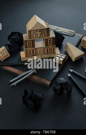 Hausbau, Planung, Kontrolle und Reparatur Konzept. Holzblock home auf einem Klemmbrett mit Zirkel, Lineal und Bleistift. Arbeiten auf einer Blaupause Stockfoto