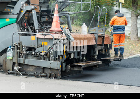 Asphalt fertiger Maschine oder fertiger Finisher Orte eine Schicht von frischem, heißem Asphalt. Straßenbau arbeiten. Straße Erneuerung. Nahaufnahme, selectiv Stockfoto