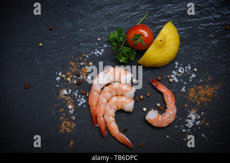 Meeresfrüchte Garnelen auf Ansicht/Schalentiere frische Garnelen Ozean Gourmet mit Tomate Zitrone grüner Petersilie Kräuter und Gewürze auf dunklem Hintergrund Stockfoto