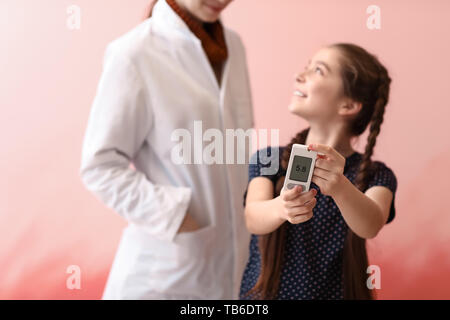 Diabetiker Mädchen mit digitalen glucometer und Arzt auf farbigen Hintergrund Stockfoto