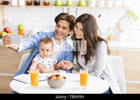 Mutter, Vater und Sohn selfie auf dem Smartphone, mit Frühstück in der Küche Stockfoto