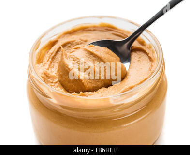 Becher und Löffel mit Erdnuß-Paste auf weißem Hintergrund. Stockfoto