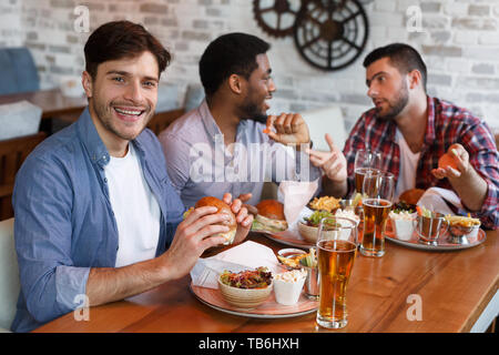 Gehilfen Zeit in die Kneipe, Essen Burger und Bier trinkt. Mann an der Kamera auf der Suche Stockfoto