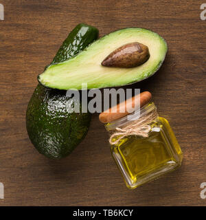 Frische avocado und das Öl im Krug auf Holz- Hintergrund, Ansicht von oben. Stockfoto