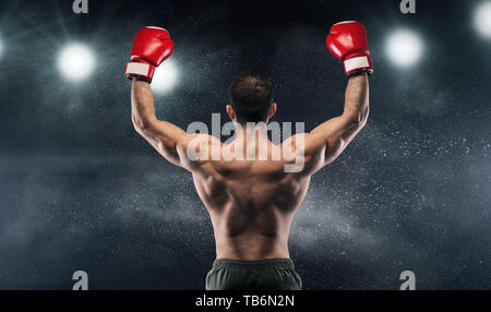 Boxer Meister seinen Sieg über die Beleuchtung genießen und Rücken an die Kamera, Schwarz studio Hintergrund Stockfoto