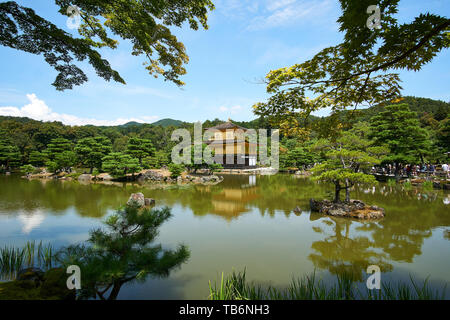 Kinkakuji (goldener Pavillon) reflektiert auf dem Wasser, umgeben von Bäumen und Besucher, an einem klaren, sonnigen Sommertag in Kyoto, Japan. Stockfoto