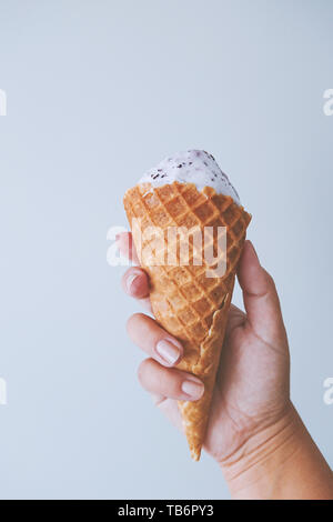 Weibliche hand Fingern halten eine Waffel Kegel mit Eis. Yami süße Speisen Sommer Konzept Stockfoto