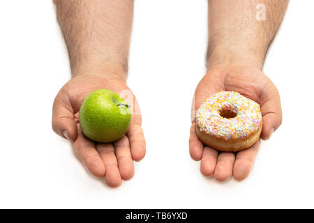 Hände halten einen Apfel und ein Donut Konzept der eine schwierige Wahl zwischen den beiden Alternativen (gesunde Ernährung vs süße Speisen) Stockfoto