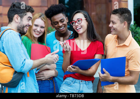 Gruppe von amerikanischen und lateinamerikanischen und afrikanischen Studenten sprechen von Hausaufgaben im Freien im Sommer Stockfoto