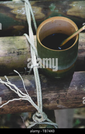 Frische bio Bambus Tasse und Löffel mit heißem köstlicher Kaffee auf einer Bank im Dschungel in Thailand gefüllt. Ökotourismus Stockfoto