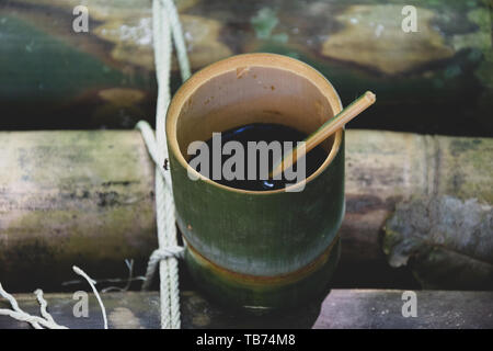 Frische bio Bambus Tasse und Löffel mit heißem köstlicher Kaffee auf einer Bank im Dschungel in Thailand gefüllt. Ökotourismus Stockfoto