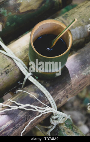 Frische bio Bambus Tasse und Löffel mit heißem köstlicher Kaffee auf einer Bank im Dschungel in Thailand gefüllt. Ökotourismus Stockfoto