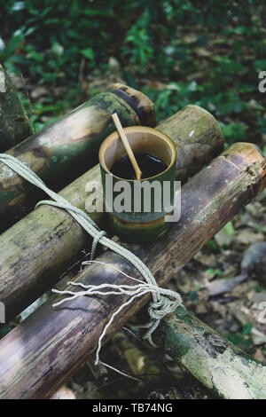 Frische bio Bambus Tasse und Löffel mit heißem köstlicher Kaffee auf einer Bank im Dschungel in Thailand gefüllt. Ökotourismus Stockfoto