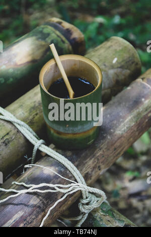 Frische bio Bambus Tasse und Löffel mit heißem köstlicher Kaffee auf einer Bank im Dschungel in Thailand gefüllt. Ökotourismus Stockfoto