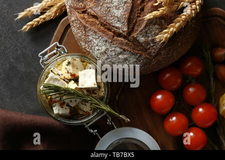 Glas Glas mit marinierten Käse und leckeres Brot auf Holzbrett Stockfoto