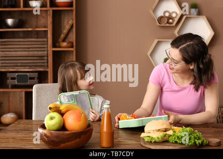 Mutter mit niedlichen Tochter Vorbereitung Schule Mittagessen zu Hause Stockfoto