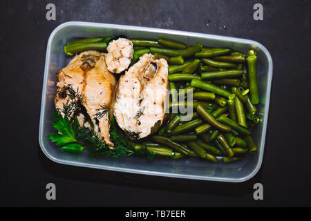 Gesunde Snack, Essen in einem Container. Gebackene rote Fische, rosa Lachs, Lachs und grüne Bohnen auf schwarzem Hintergrund schließen oben. top anzeigen, kopieren. Gesunde fo Stockfoto