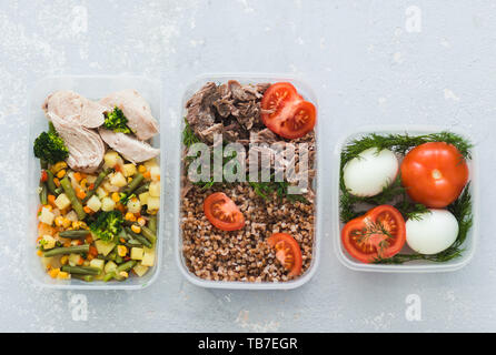 Ernährung Lebensmittel in den drei Behältern auf einem grauen Hintergrund. Gekochte und frischem Gemüse, Buchweizen, Eier, Rindfleisch, Huhn. top View Stockfoto