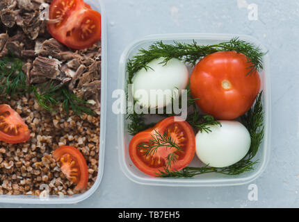 Ernährung Lebensmittel in den drei Behältern auf einem grauen Hintergrund. Gekochte und frischem Gemüse, Buchweizen, Eier, Rindfleisch, Huhn, Dill. top View Stockfoto