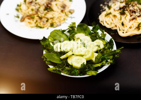 Köstliches Abendessen oder Mittagessen auf einem schwarzen Holz- hintergrund, in der Nähe von frischem Grün Kräuter Dill, Spinat, Zwiebel, Petersilie und Gurke Gemüse in einer Platte Stockfoto