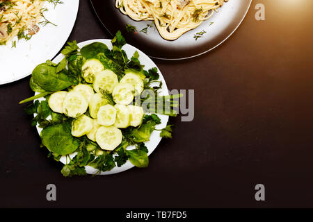 Nahaufnahme der leckere Pasta mit Pilzen und Grüns in einen Teller auf einem schwarzen Hintergrund. Gesunde Ernährung, gute Ernährung Konzepte. Stockfoto