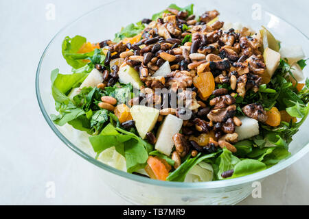 Pinienkernen Salat mit Walnuss, Birne, getrockneten Aprikosen, Rucola oder Rucola Blätter in Glasschale. Ökologische Lebensmittel. Stockfoto