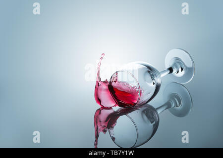 Rotwein aus einem sinkenden Glas spiegelt sich auf der Oberfläche verschüttet Stockfoto