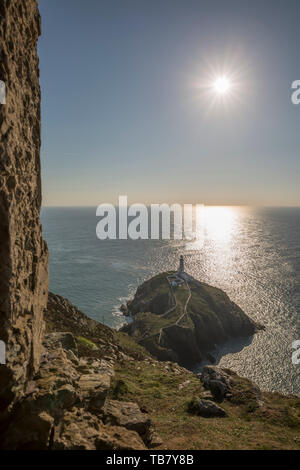 Wunderschöne walisische Landschaft: South Stack Leuchtturm auf Holy Island bei Sonnenuntergang, Holyhead, Anglesey, Wales Großbritannien. Helle Sonnenstrahlen glitzern im Meer. Stockfoto