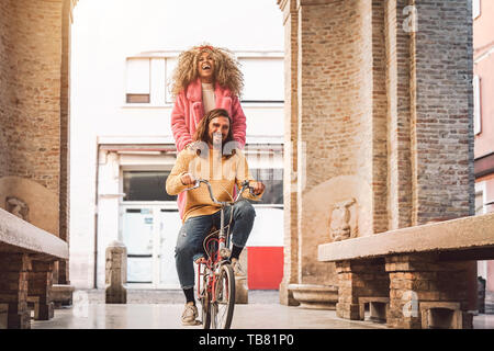 Glückliches Paar gehen mit dem Fahrrad in die Innenstadt - junge Menschen, die Spaß im Freien - Millenniums-generation und Jugend lifestyle Konzept Stockfoto