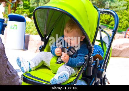 Kleiner Junge sitzt in Pram mit einem lächelnden Gesicht Stockfoto