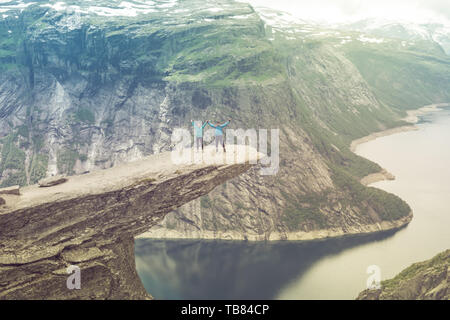 Paar posiert auf Trolltunga. Froh, dass Frau und Mann schönen See und gutes Wetter in Norwegen genießen. Stockfoto