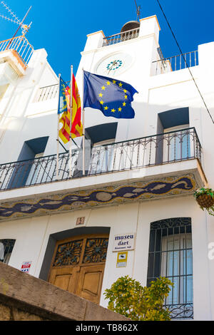 Calpe, Alicante, Spanien. Mai 10, 2019: Kunst Museum Hausfassade mit Uhr und die Fahnen der autonomen Gemeinschaft Valencia, Spanien und die Europäische Gemeinschaft Stockfoto