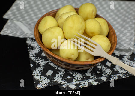 Gewaschen frischen, rohen Kartoffeln auf einer Platte bereit für das Kochen. Der dunkle Hintergrund. Stockfoto