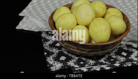 Gewaschen frischen, rohen Kartoffeln auf einer Platte bereit für das Kochen. Der dunkle Hintergrund. Stockfoto