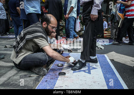 Teheran, Iran. 31. Mai, 2019. Eines Irani Mann putzt die Schuhe für staubbeutel Mann stand auf der israelischen Flagge während eines Protestes Kennzeichnung der jährlichen al-Quds (Jerusalem) am letzten Freitag des muslimischen Fastenmonats Ramadan. Credit: Saeid Zareian/dpa/Alamy leben Nachrichten Stockfoto