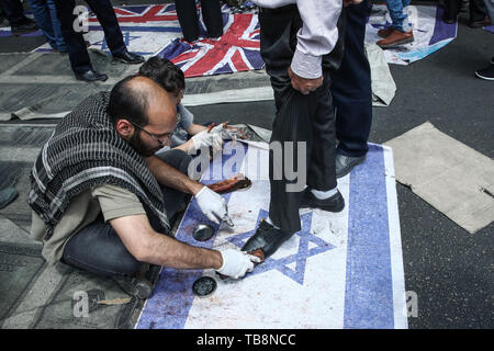 Teheran, Iran. 31. Mai, 2019. Eines Irani Mann putzt die Schuhe für staubbeutel Mann stand auf der israelischen Flagge während eines Protestes Kennzeichnung der jährlichen al-Quds (Jerusalem) am letzten Freitag des muslimischen Fastenmonats Ramadan. Credit: Saeid Zareian/dpa/Alamy leben Nachrichten Stockfoto